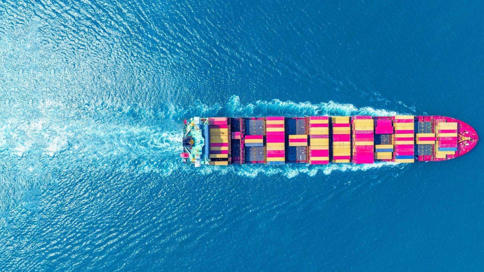 A warehouse worker sorts boxes from a container onto pallets and a conveyor belt for parcels.